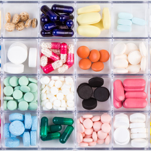 Various medicine pills and capsules in a plastic pill organizer.