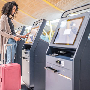 Woman using the check-in machine at the airport, getting the boarding pass.