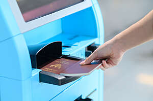 Close view of a woman's hand scanning her passport at an airport scanning machine.